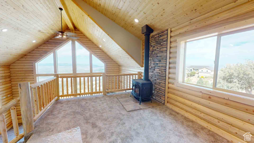 Bonus room with rustic walls, a wood stove, healthy amount of natural light, carpet floors, and wooden ceiling