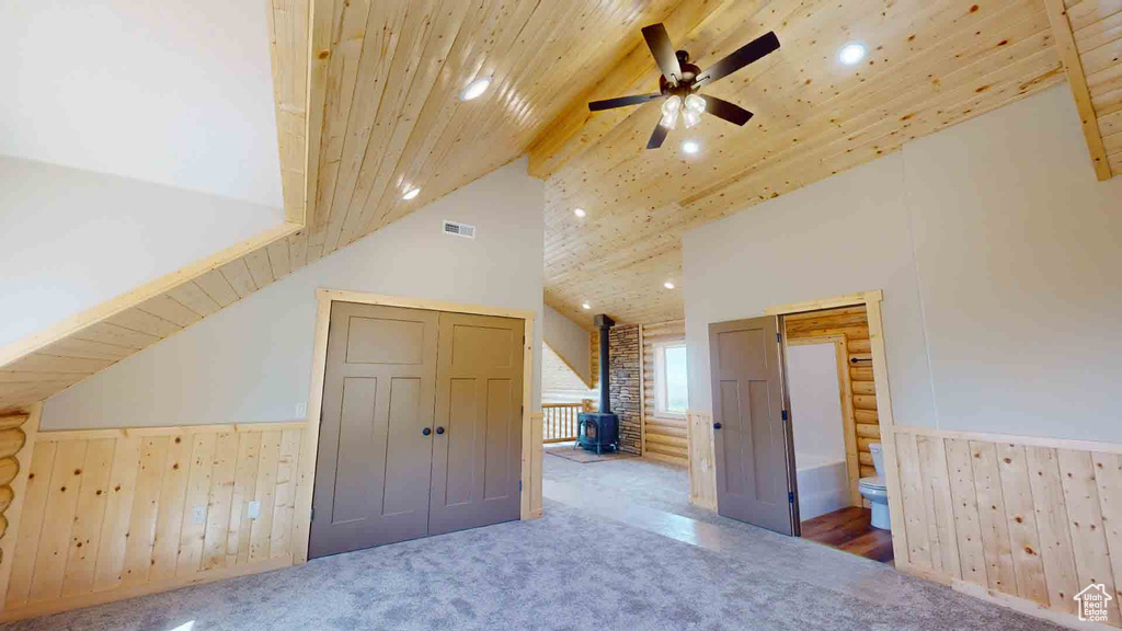 Bonus room featuring a wood stove, wainscoting, recessed lighting, carpet, and a ceiling fan