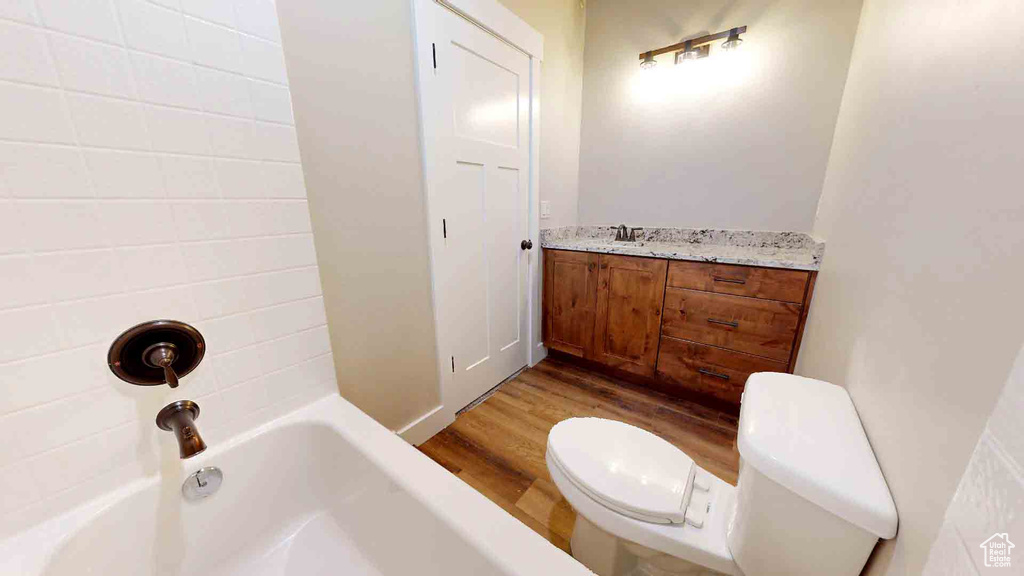 Bathroom with toilet, wood finished floors, and a sink