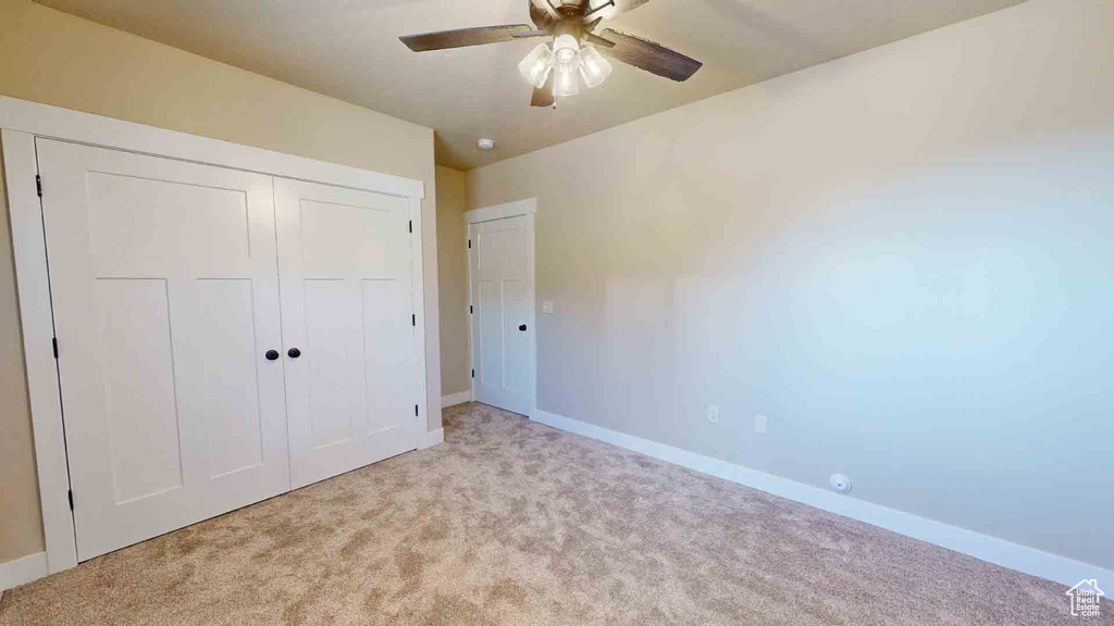 Unfurnished bedroom with carpet, baseboards, a closet, and a ceiling fan