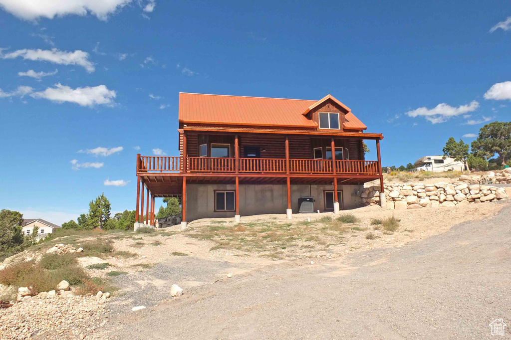 Back of house with metal roof, a wooden deck, and log siding