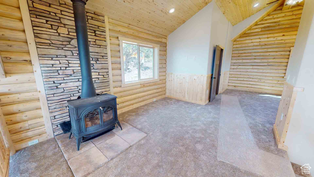 Unfurnished living room with a wood stove, rustic walls, carpet, wood ceiling, and recessed lighting