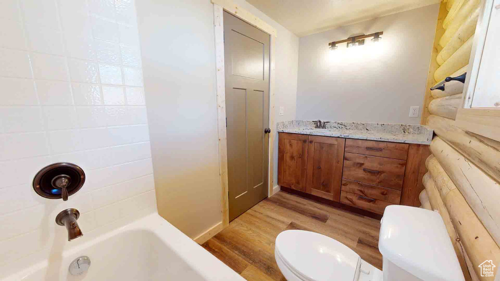 Full bathroom with wood finished floors, toilet,  shower combination, and vanity