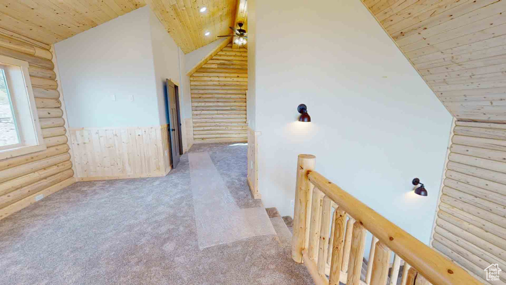 Hall featuring log walls, wooden ceiling, vaulted ceiling, carpet flooring, and an upstairs landing