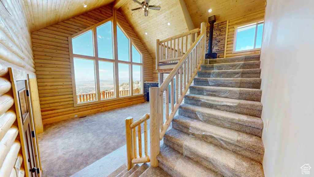 Staircase with carpet, wooden ceiling, high vaulted ceiling, a ceiling fan, and rustic walls