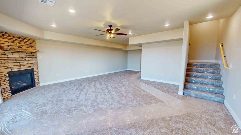 Unfurnished living room with carpet, ceiling fan, a fireplace, stairs, and recessed lighting