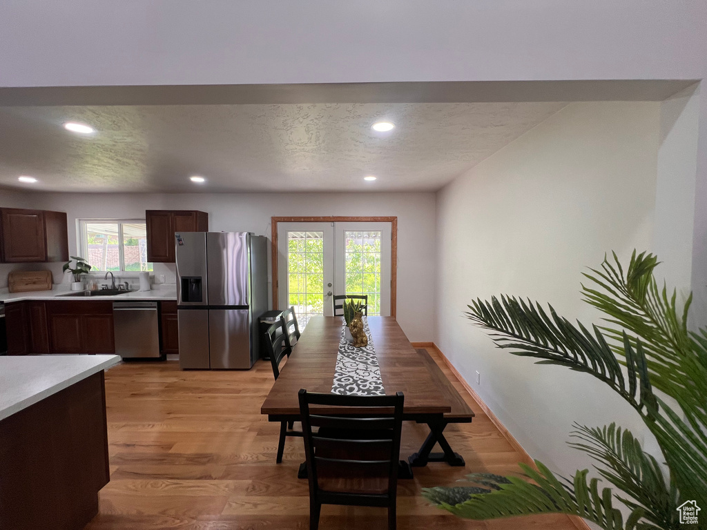 Dining room with french doors, a textured ceiling, recessed lighting, light wood-style flooring, and baseboards