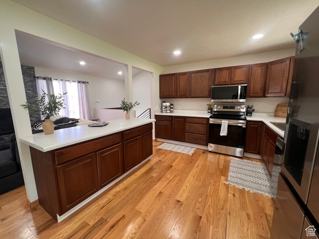 Kitchen with stainless steel appliances, light countertops, light wood-style flooring, and recessed lighting