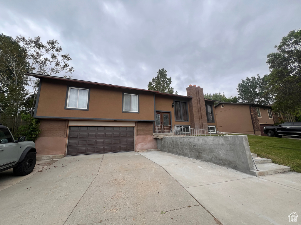 Split foyer home with an attached garage, concrete driveway, and stucco siding