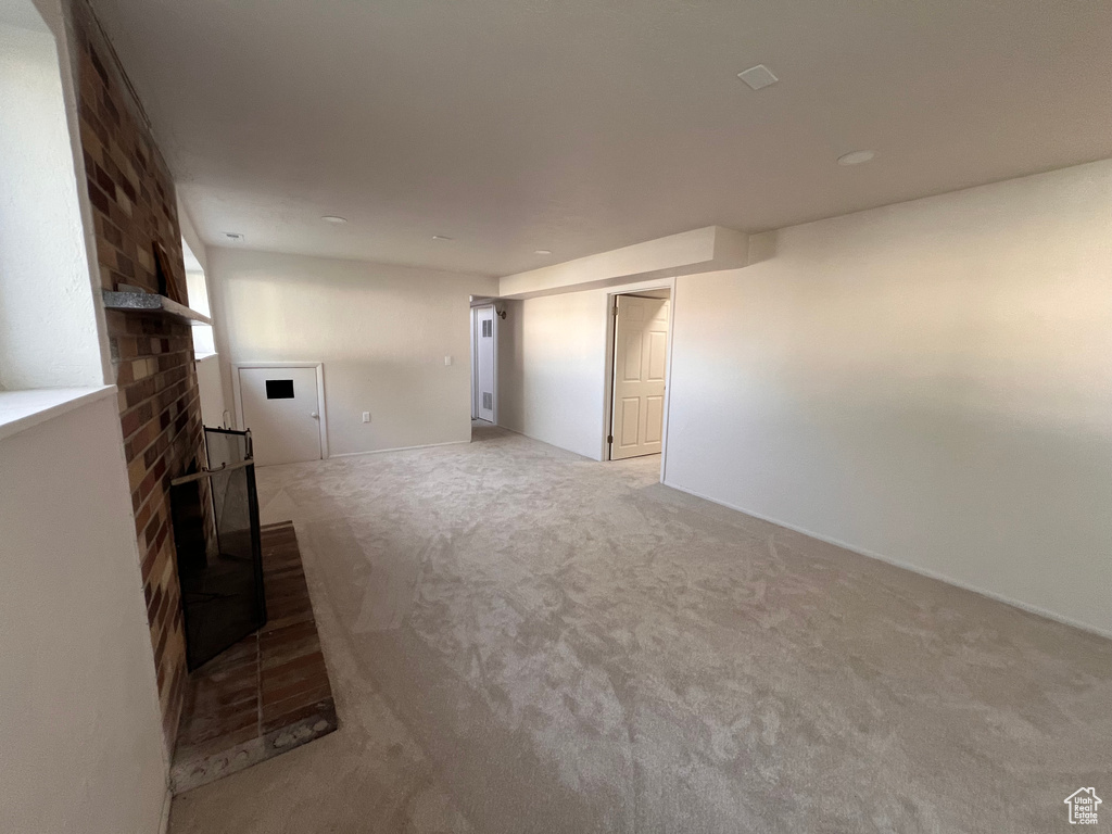 Unfurnished living room featuring carpet floors and a brick fireplace