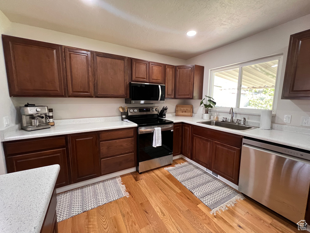Kitchen featuring stainless steel appliances, a sink, light countertops, and recessed lighting