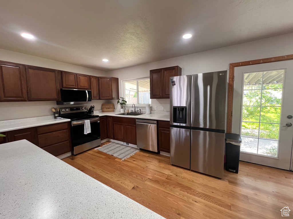 Kitchen featuring stainless steel appliances, light countertops, recessed lighting, a sink, and light wood-style flooring
