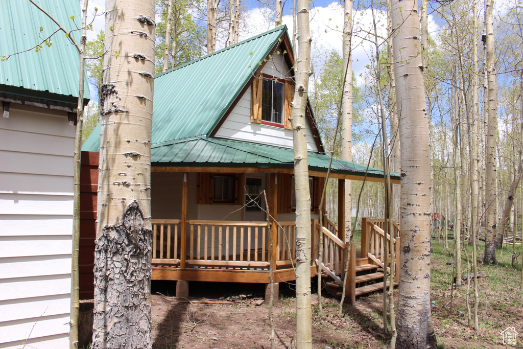 View of property exterior with a porch and metal roof