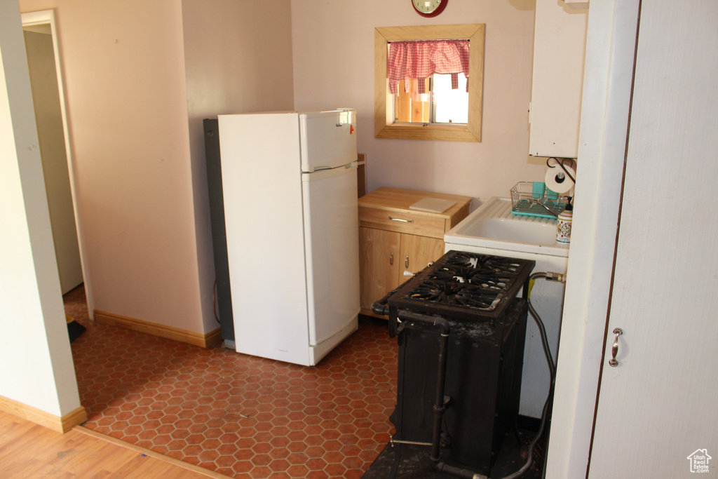 Kitchen with freestanding refrigerator, baseboards, light countertops, and water heater