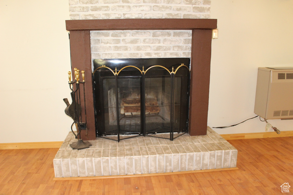 Detailed view of a brick fireplace, wood finished floors, and baseboards