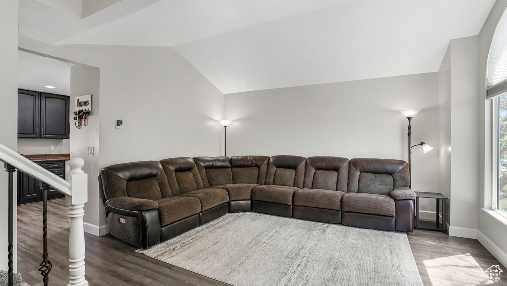 Living area featuring wood finished floors, baseboards, healthy amount of natural light, and lofted ceiling