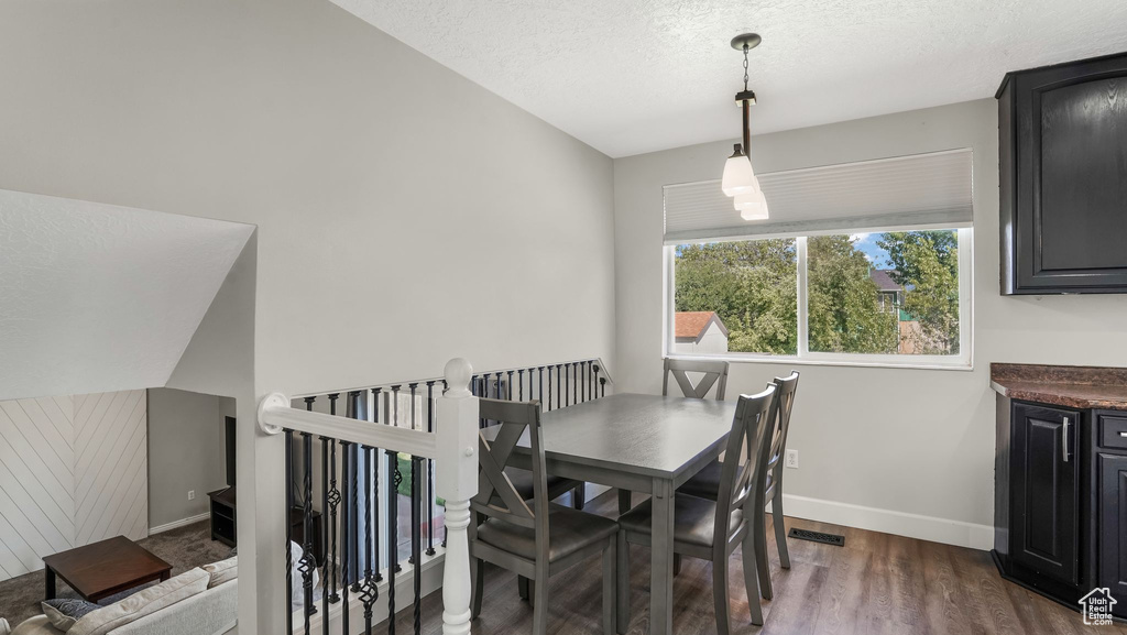 Dining space with dark wood-type flooring, baseboards, and a textured ceiling