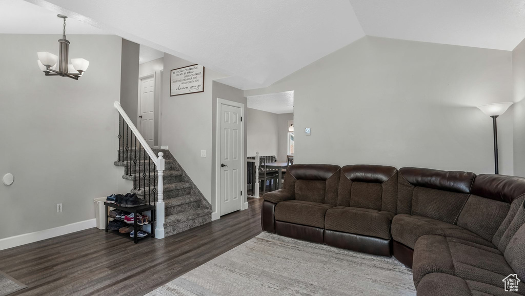 Living room featuring a chandelier, wood finished floors, stairway, vaulted ceiling, and baseboards