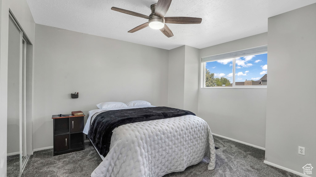 Carpeted bedroom with baseboards, a textured ceiling, a ceiling fan, and a closet