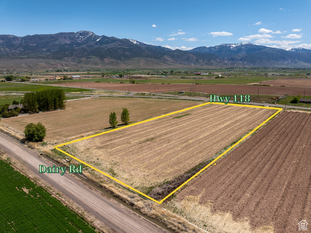 Aerial view of sparsely populated area with large plots for crops, property parcel outlined, and a mountain backdrop