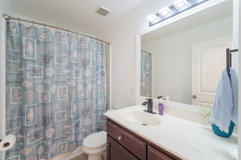 Bathroom with vanity, toilet, and a shower with shower curtain