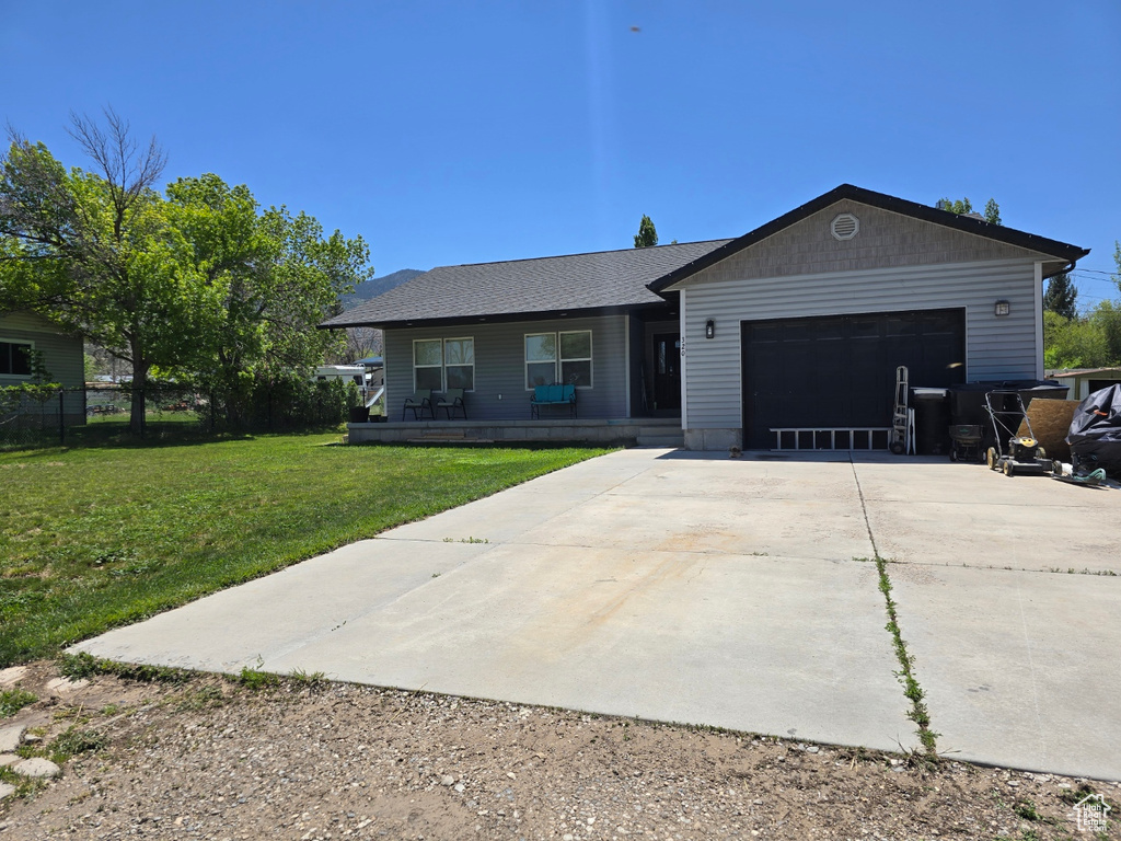 Single story home with concrete driveway, a garage, a front yard, and a porch