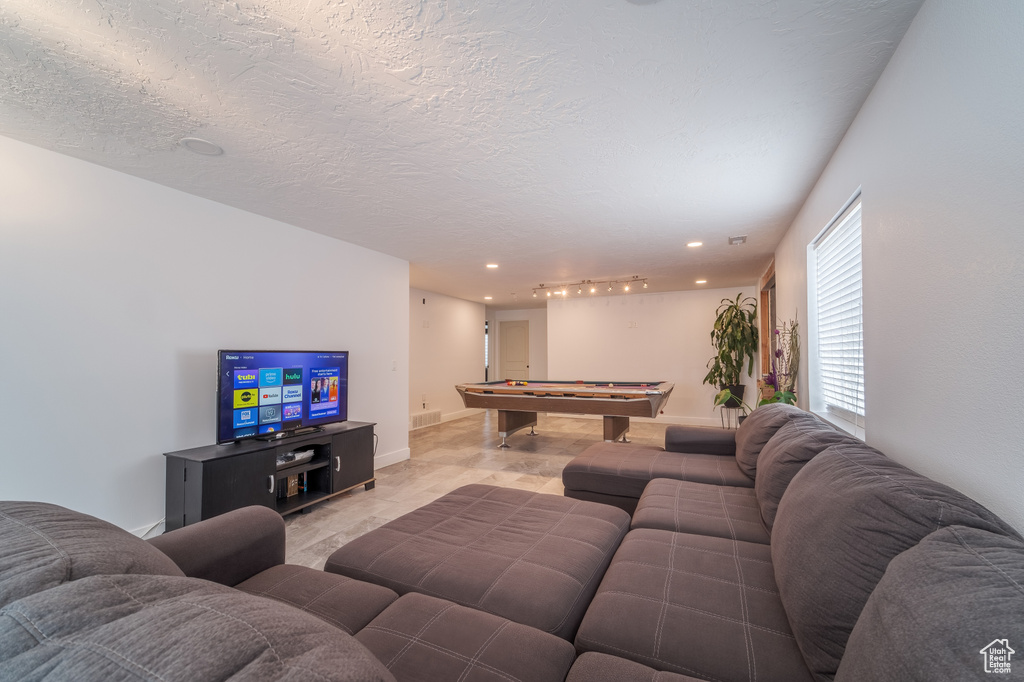 Living room featuring pool table, a textured ceiling, and recessed lighting