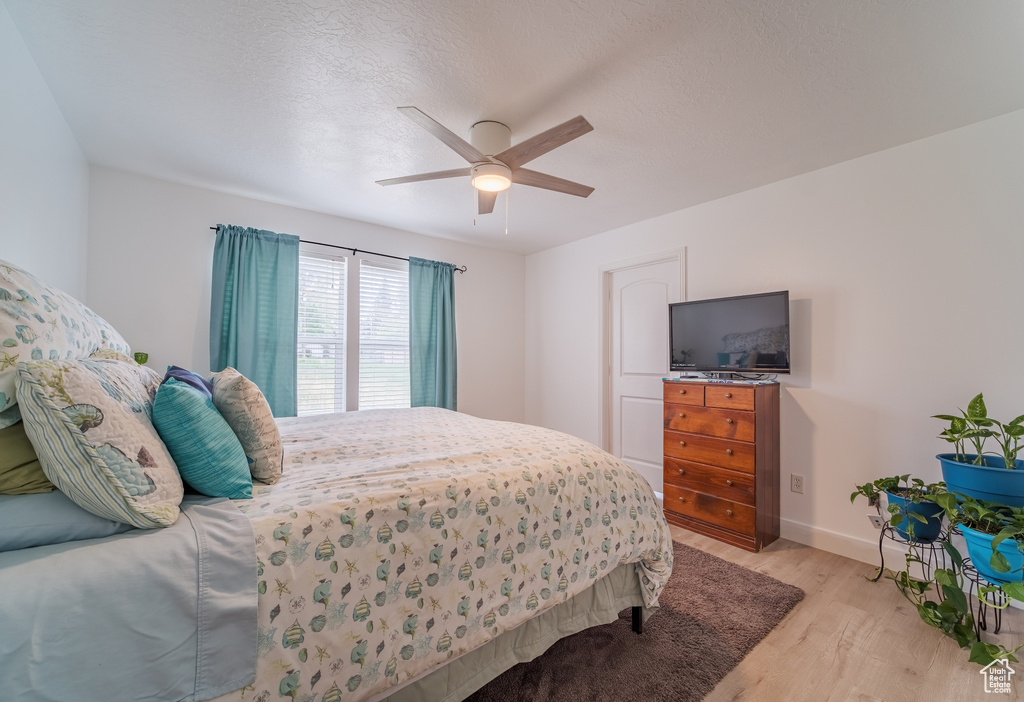 Bedroom with light wood-style floors, baseboards, and a ceiling fan