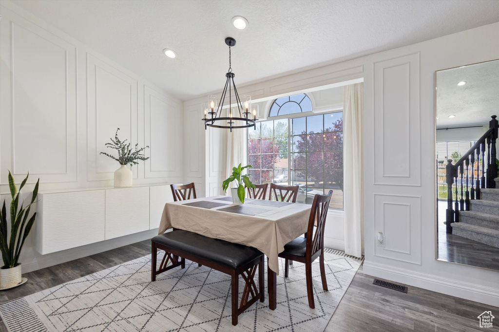 Dining space with a chandelier, plenty of natural light, a decorative wall, light wood finished floors, and recessed lighting
