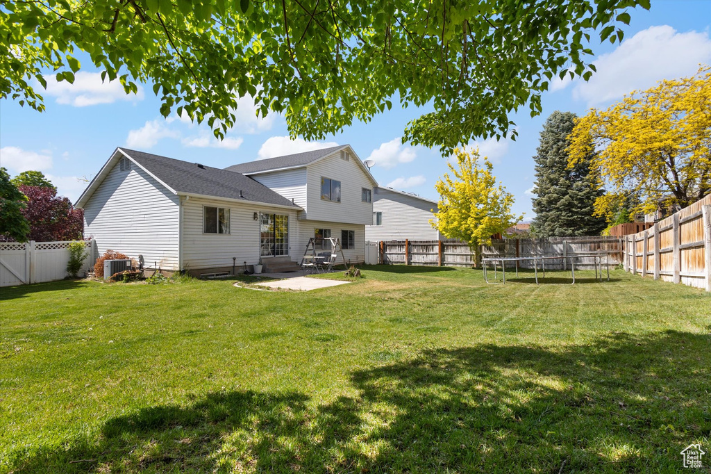 Rear view of house featuring a trampoline, central air condition unit, and a patio