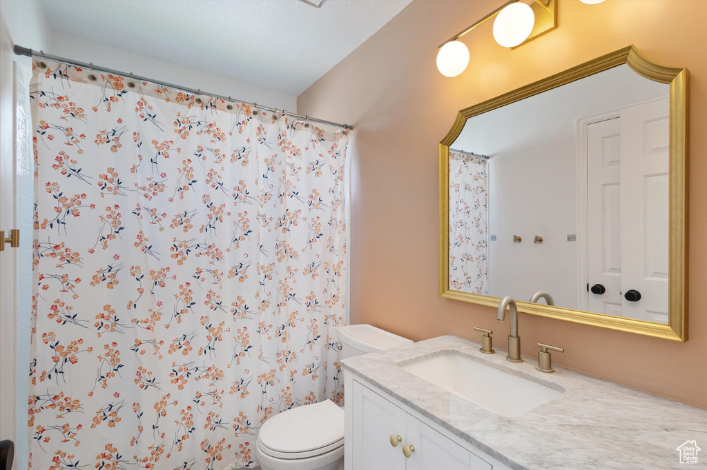 Bathroom with toilet, vanity, and a shower with shower curtain