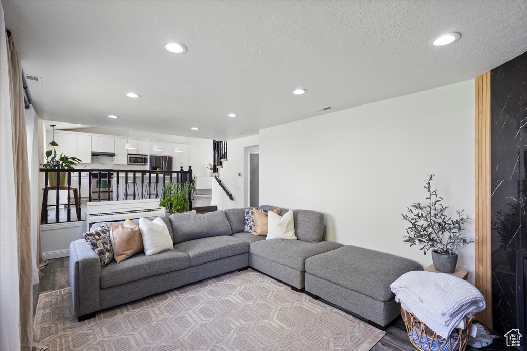 Living room with recessed lighting, light wood-style flooring, stairway, and a textured ceiling