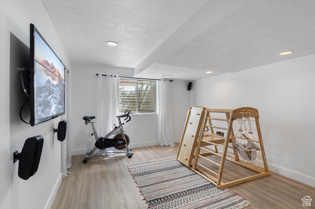 Exercise area with a textured ceiling, baseboards, wood finished floors, and recessed lighting