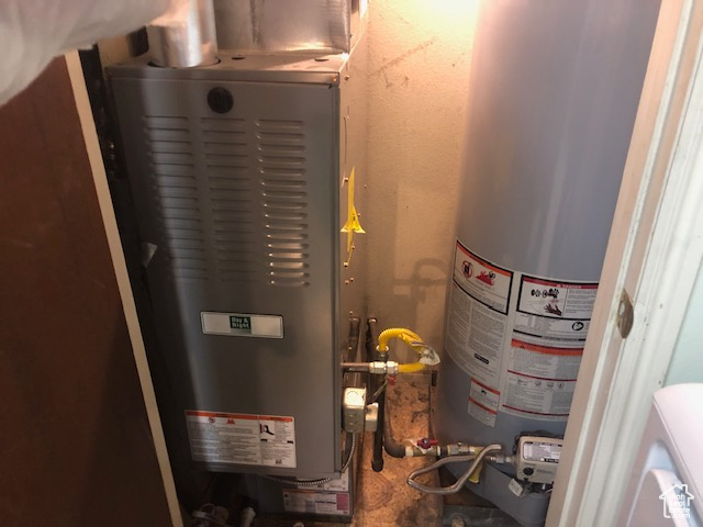Utility room featuring water heater and heating unit