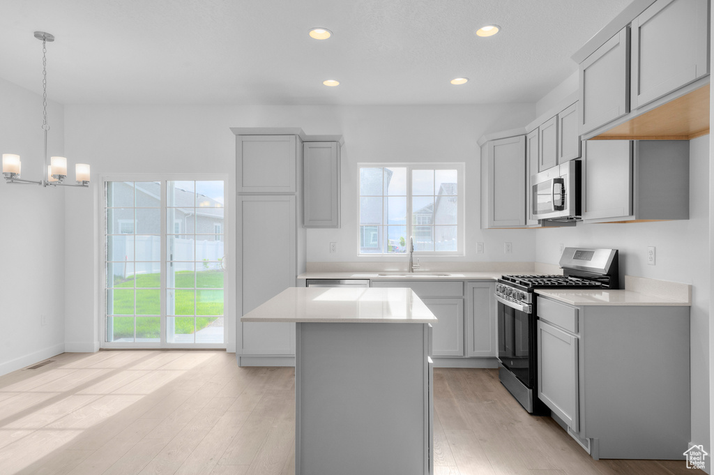 Kitchen featuring stainless steel appliances, a sink, a center island, a chandelier, and light countertops