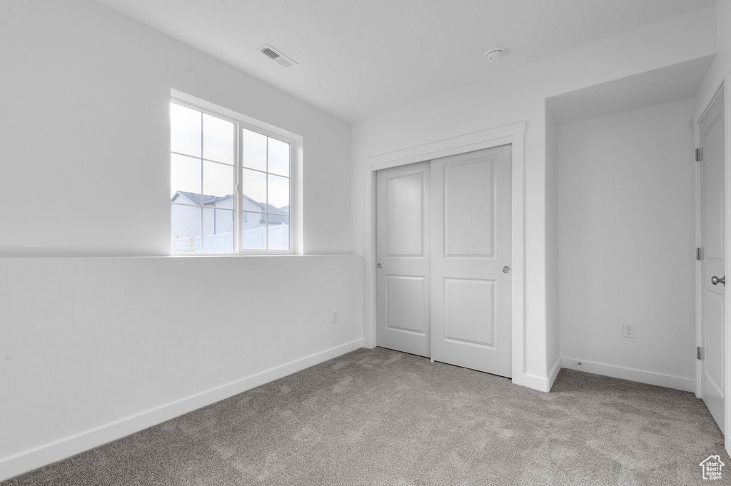 Unfurnished bedroom featuring carpet, baseboards, and a closet