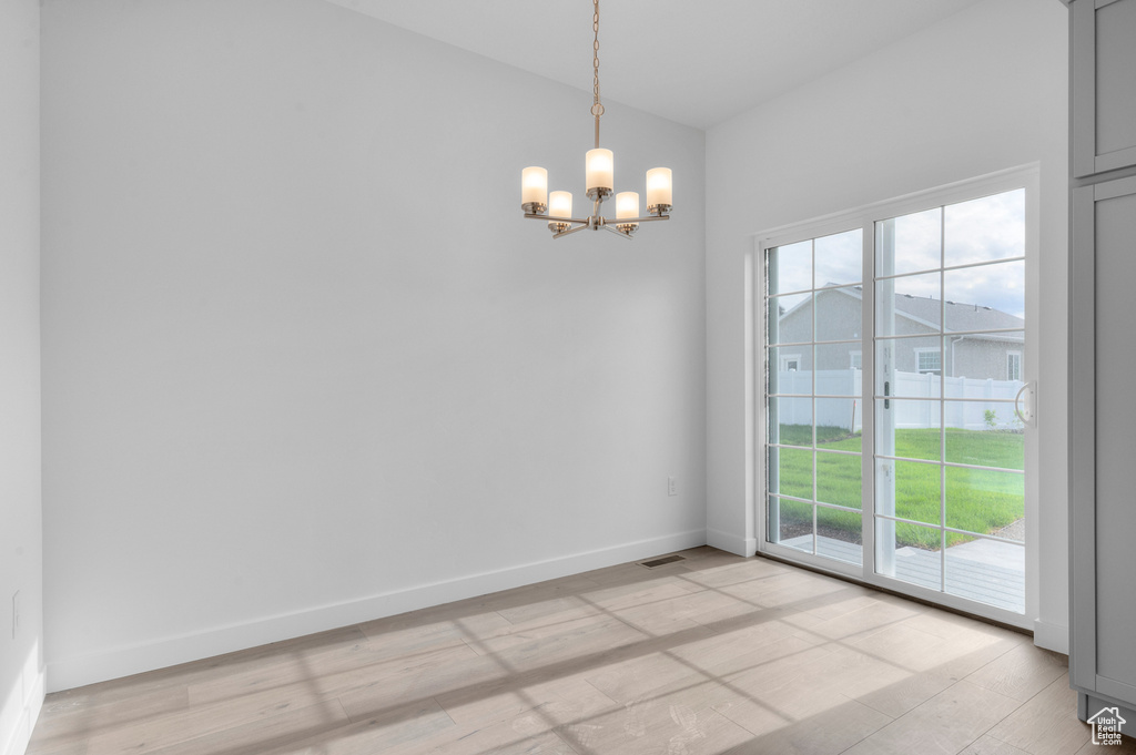 Spare room featuring a chandelier, baseboards, and light wood-style flooring