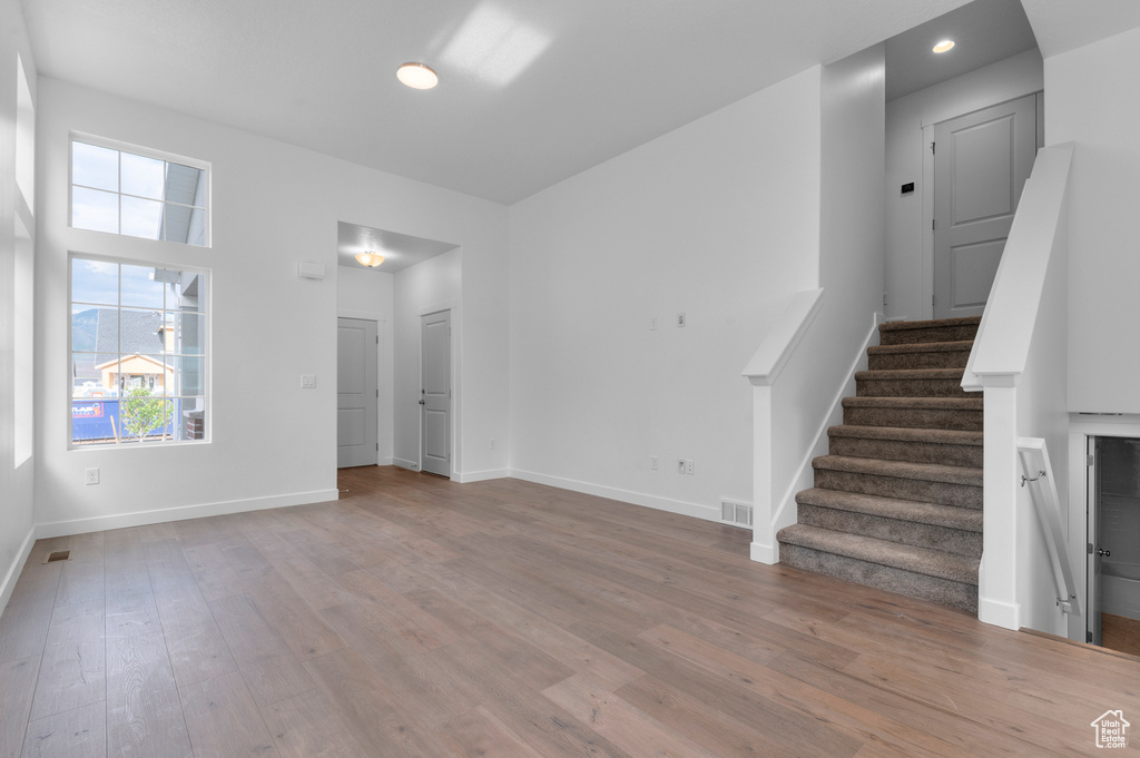 Unfurnished living room with light wood-style floors, stairs, baseboards, and recessed lighting