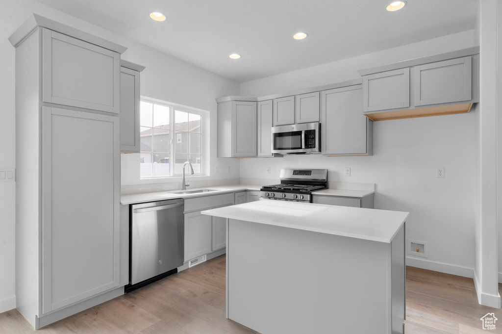 Kitchen featuring stainless steel appliances, a sink, a center island, light countertops, and recessed lighting