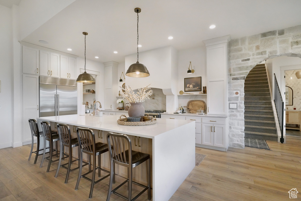 Kitchen with built in fridge, white cabinetry, light wood-style flooring, a spacious island, and recessed lighting