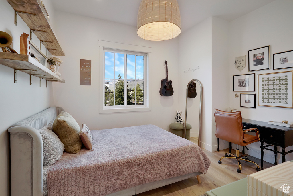 Bedroom with light wood-style flooring, baseboards, and a desk