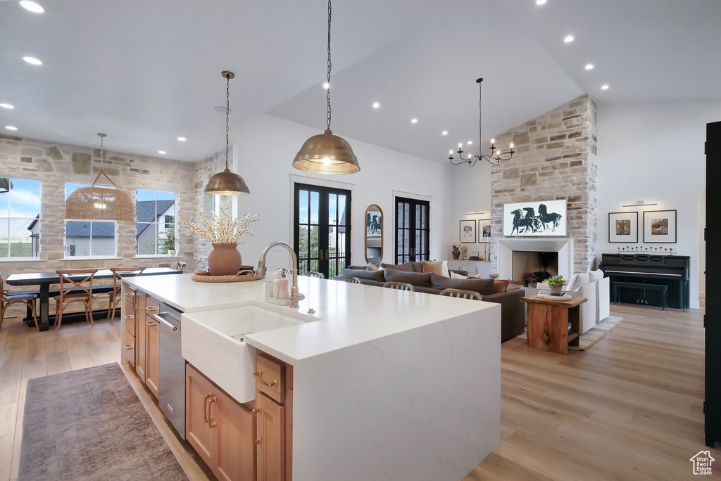 Kitchen with a sink, high vaulted ceiling, light wood-style floors, light countertops, and stainless steel dishwasher