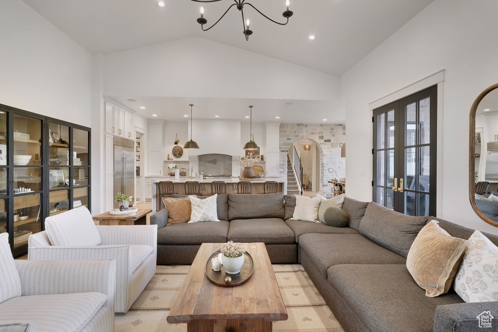 Living room featuring arched walkways, a chandelier, and high vaulted ceiling