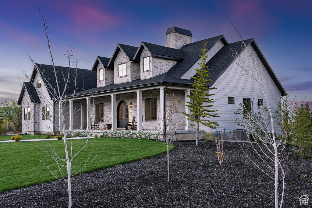 View of front of home featuring a porch, a chimney, a front yard, and central AC unit