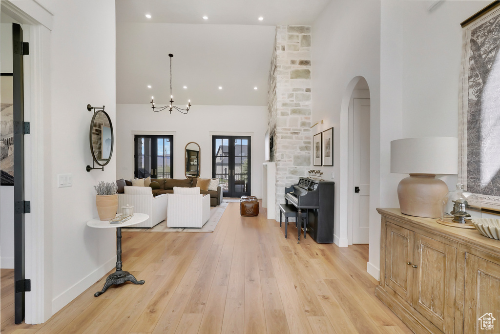 Foyer with high vaulted ceiling, baseboards, light wood-type flooring, arched walkways, and recessed lighting