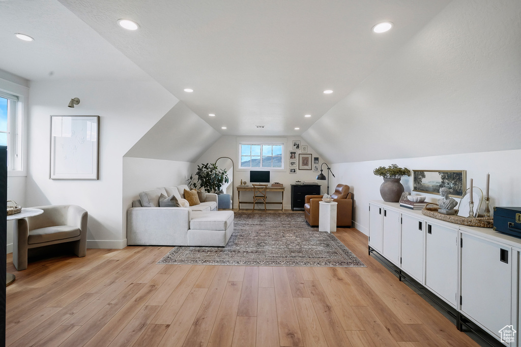 Living area with light wood-type flooring, baseboards, lofted ceiling, an office area, and recessed lighting