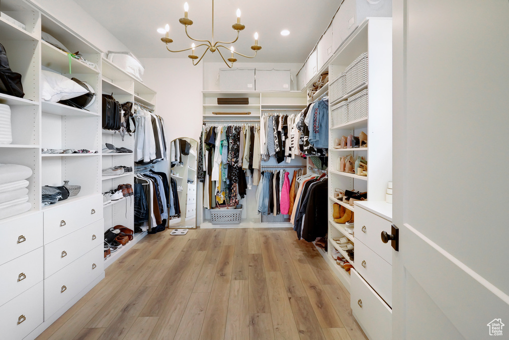 Walk in closet with a chandelier and light wood-style flooring