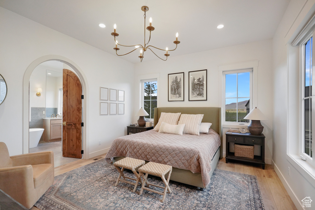 Bedroom with arched walkways, light wood-style flooring, a chandelier, recessed lighting, and baseboards