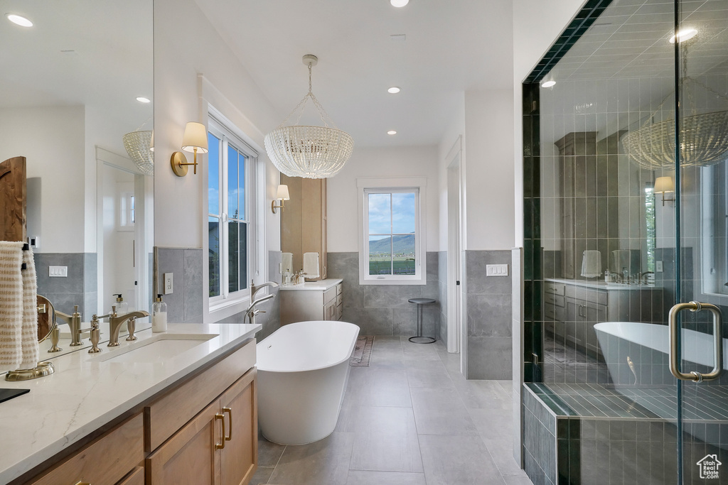 Bathroom with tile walls, tile patterned flooring, a chandelier, a wainscoted wall, and a stall shower