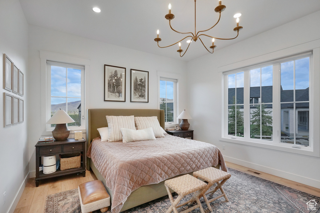Bedroom with light wood-style floors, a chandelier, and baseboards